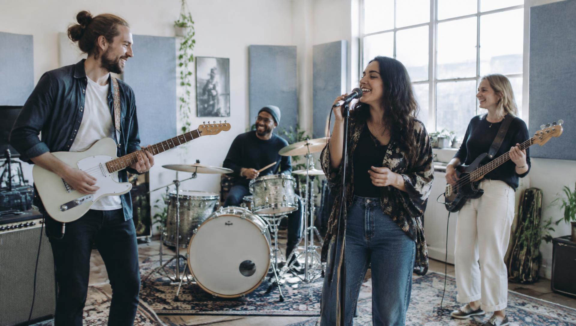 Four-piece band rehearsing together in a sunlit rehearsal room